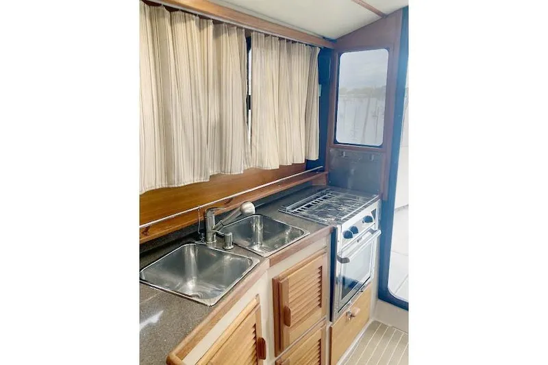 Slide: The Image of 2016 Ranger Tugs R-31 galley with dual sinks, stove, and wooden cabinetry. - 19