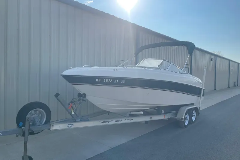 Slide: The Image of 1996 Four Winns 200 Horizon boat on trailer, parked beside a large building. - 2