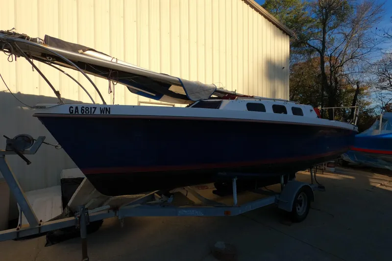 The Image of 1986 Rhodes 22 sailboat on trailer, parked outdoors near a building. - 0