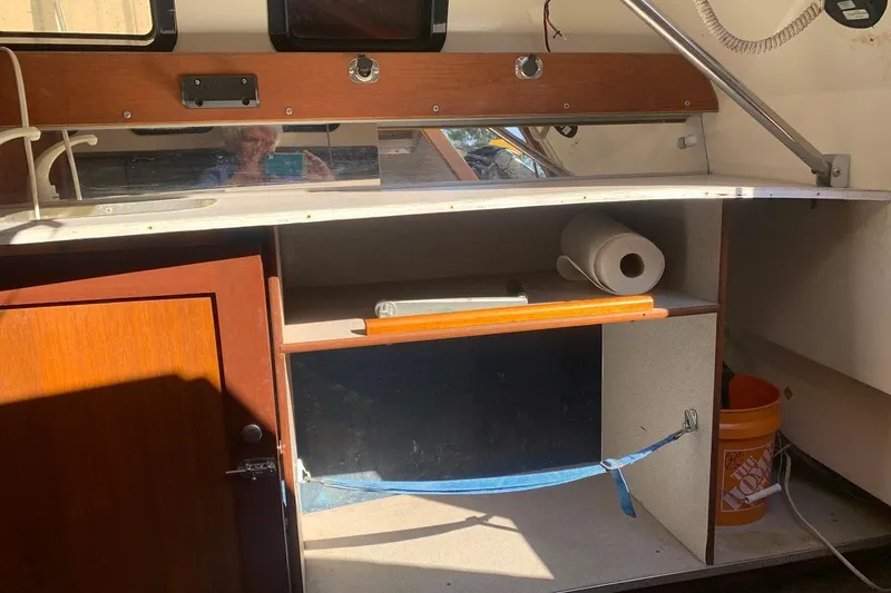 Slide: The Image of Interior of a 1986 Rhodes 22 sailboat with storage and wooden cabinetry. - 12