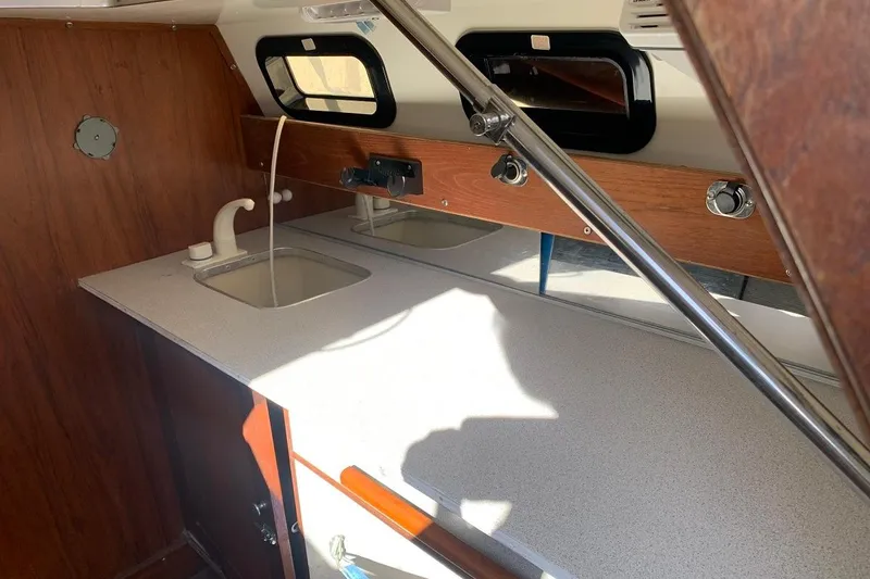Slide: The Image of 1986 Rhodes 22 sailboat interior with sink and wooden cabinetry. - 13