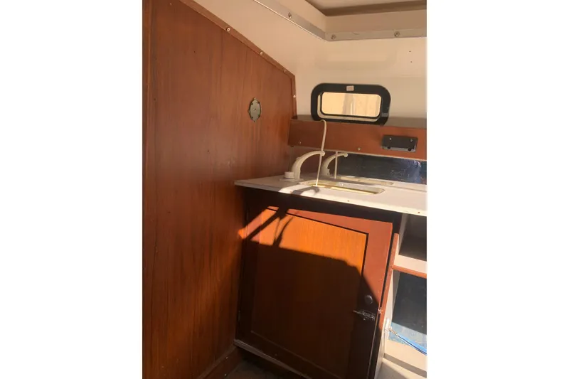 Slide: The Image of Interior of a 1986 Rhodes 22 sailboat featuring a compact wooden kitchenette. - 14