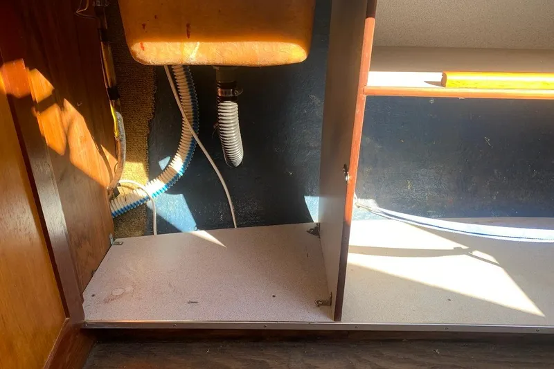 Slide: The Image of 1986 Rhodes 22 interior showing under-sink plumbing and storage area. - 15