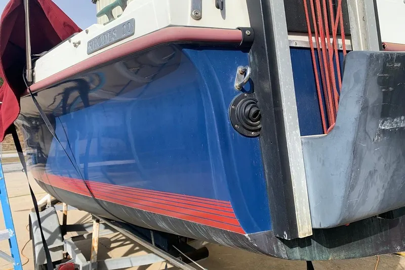 Slide: The Image of 1986 Rhodes 22 sailboat with blue hull and red accents on a trailer. - 4