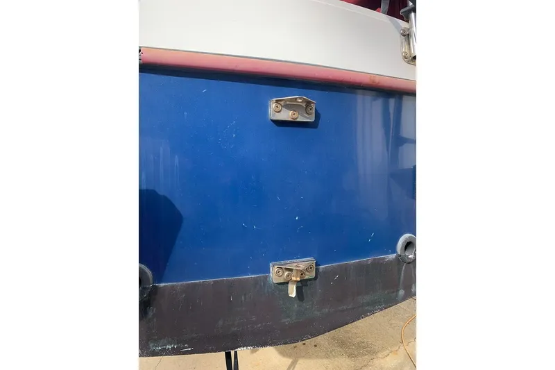 Slide: The Image of 1986 Rhodes 22 boat hull with blue and white exterior, featuring metal fittings. - 5