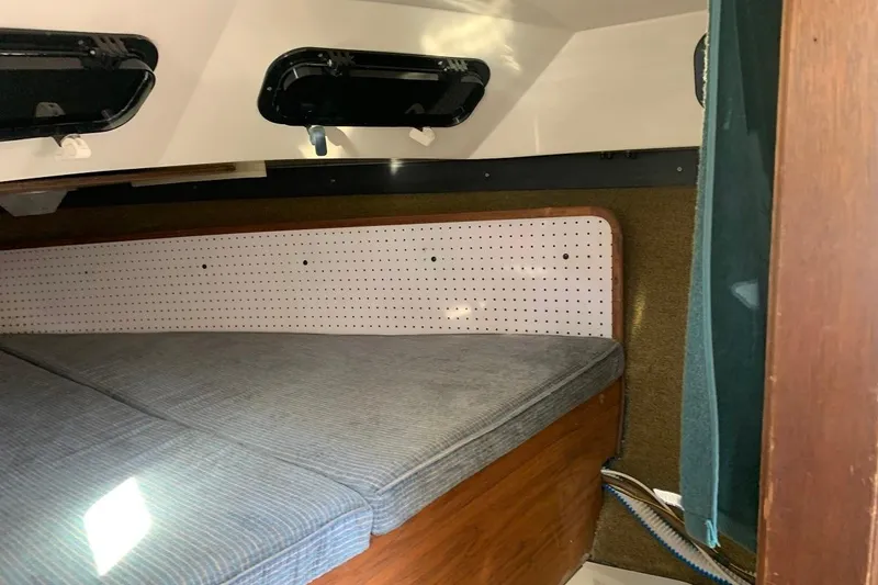 Slide: The Image of Interior cabin of a 1986 Rhodes 22 sailboat with cushioned seating and portholes. - 8