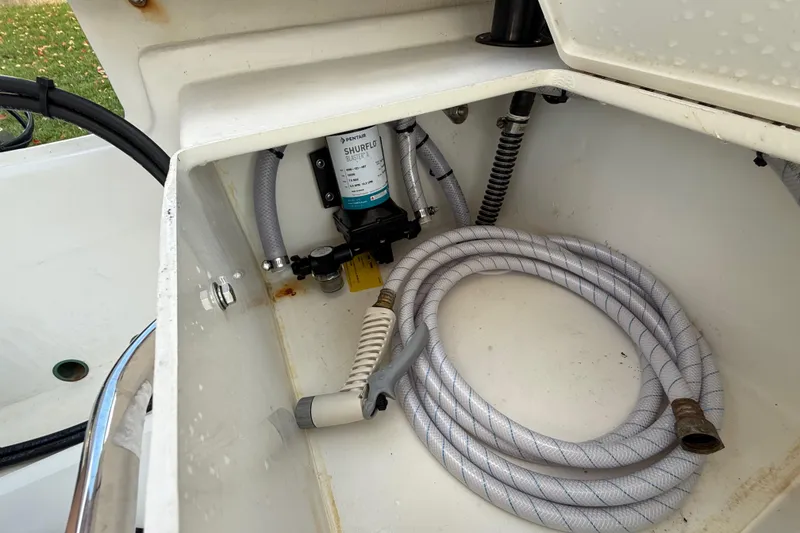 Slide: The Image of 2024 Parker 1801 Center Console boat compartment with Shurflo pump and coiled hose. - 38