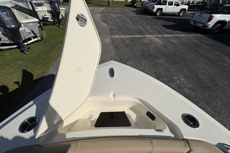 Slide: The Image of 2026 Scout 222 Dorado boat bow storage compartment open, parked near trucks and outboard motors. - 25