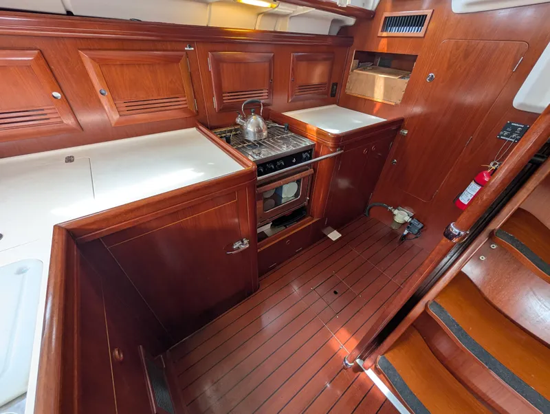 Slide: The Image of 2003 Beneteau Oceanis 473 yacht kitchen with wooden cabinetry and stove. - 14