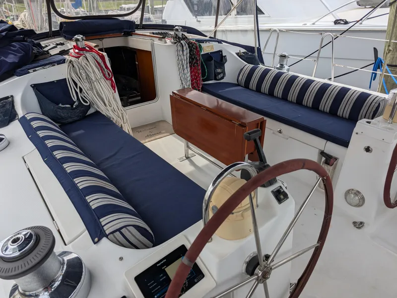 Slide: The Image of Cockpit of 2003 Beneteau Oceanis 473 sailboat with striped cushions and wooden table. - 30