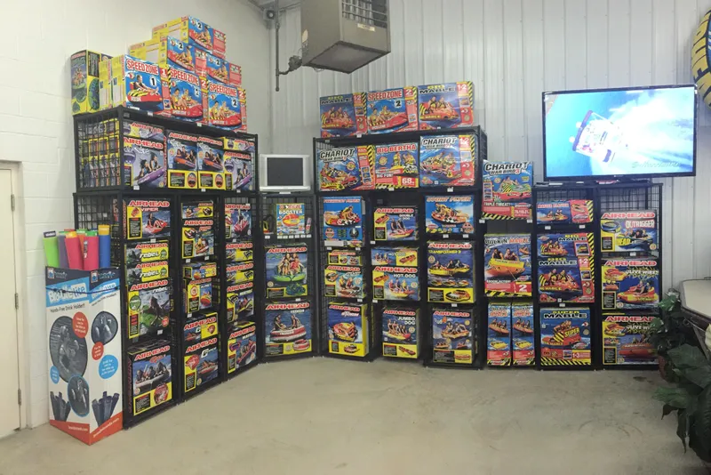 Slide: The Image of Wall of colorful inflatable water sports products in a showroom, featuring various Airhead and Sportsstuff items. - 13