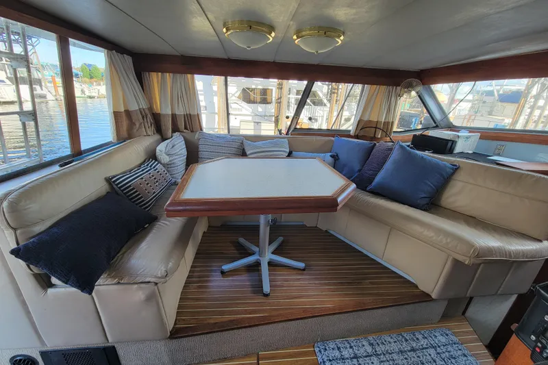 Slide: The Image of 1989 Bayliner 3888 Motoryacht interior with cozy seating and table, featuring nautical decor. - 24
