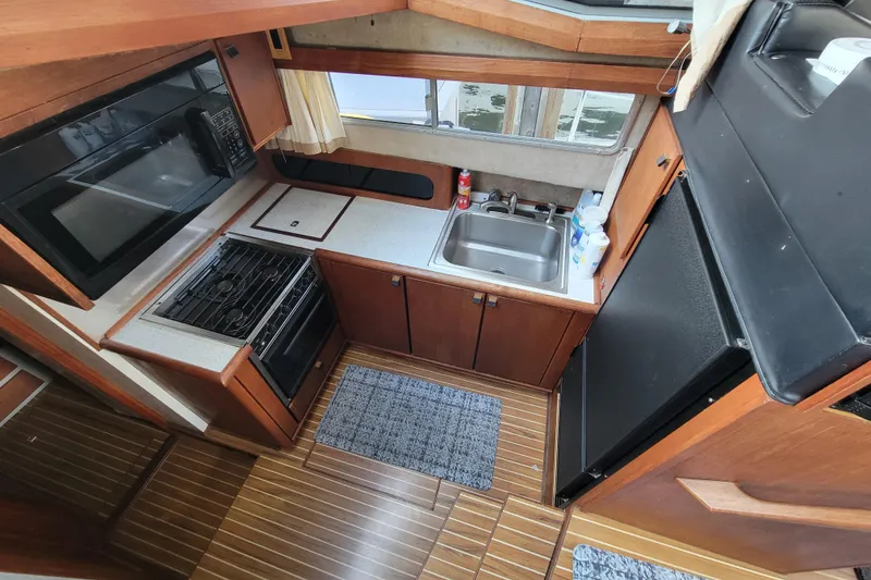 Slide: The Image of 1989 Bayliner 3888 Motoryacht kitchen with stove, sink, and wooden cabinetry. - 33