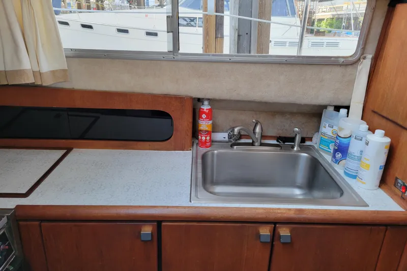 Slide: The Image of 1989 Bayliner 3888 Motoryacht kitchen with sink, cleaning supplies, and window view. - 35