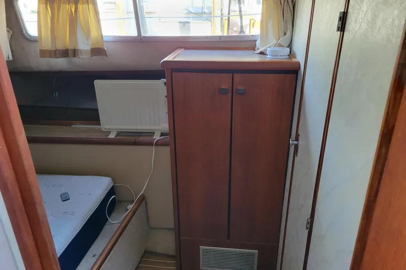 Slide: The Image of 1989 Bayliner 3888 Motoryacht interior with wooden cabinet and bed, natural light through windows. - 38
