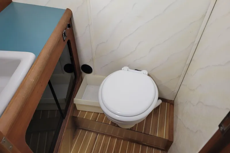 Slide: The Image of 1989 Bayliner 3888 Motoryacht bathroom with toilet and sink, featuring wood accents. - 48