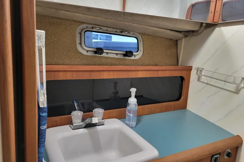 Slide: The Image of 1989 Bayliner 3888 Motoryacht bathroom with sink, faucet, and porthole window. - 49