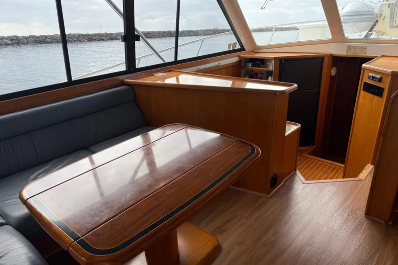 Slide: The Image of 1998 Riviera Convertible yacht interior with wooden table and seating, overlooking the water. - 20