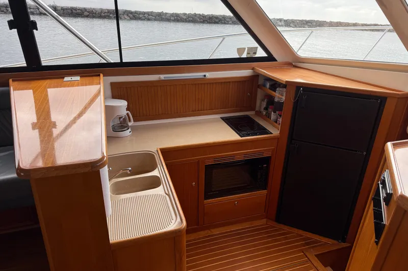 Slide: The Image of 1998 Riviera Convertible yacht kitchen with sink, stove, and refrigerator, overlooking the water. - 21