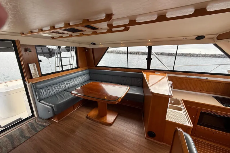 Slide: The Image of 1998 Riviera Convertible yacht interior with dining area, wooden table, and panoramic windows. - 19