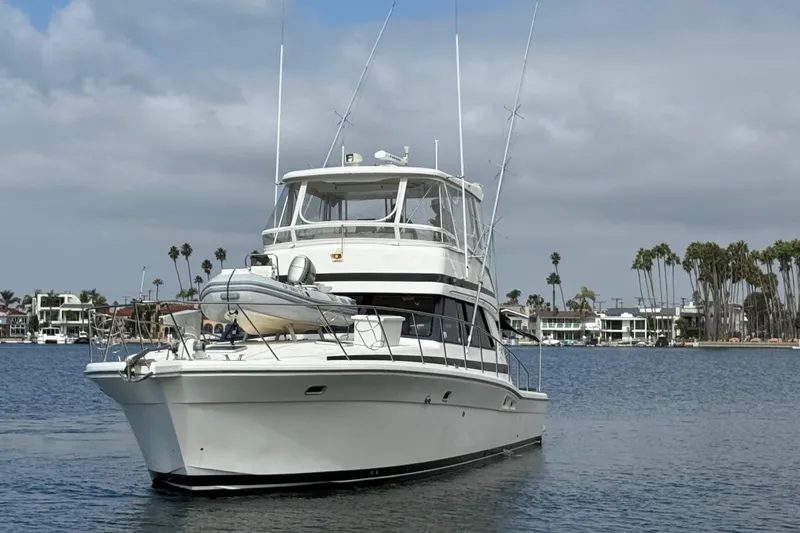 Slide: The Image of 1998 Riviera Convertible yacht on calm water with palm trees in the background. - 2