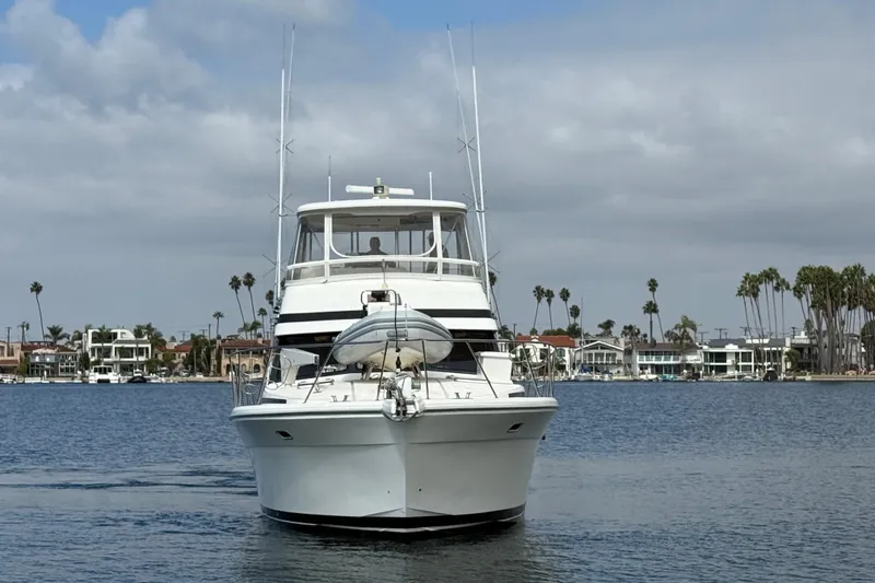 Slide: The Image of 1998 Riviera Convertible yacht on calm water with coastal homes in the background. - 3