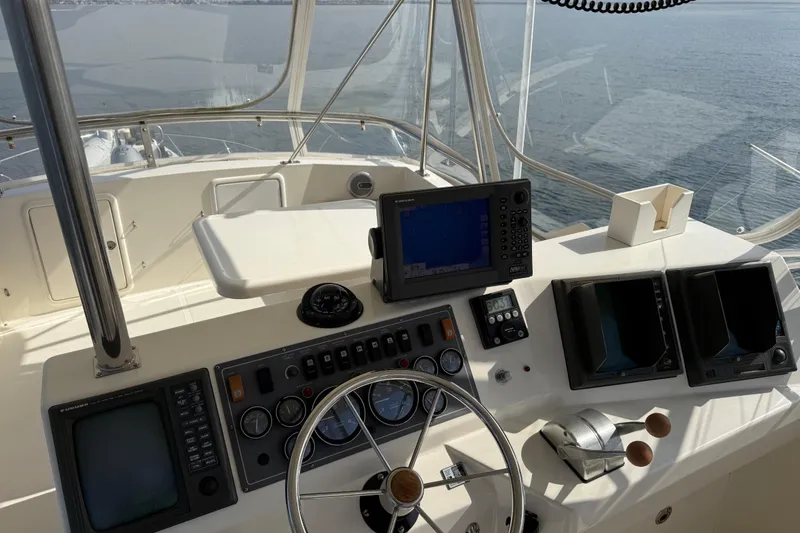 Slide: The Image of 1998 Riviera Convertible yacht helm with navigation equipment and steering wheel, overlooking calm waters. - 43