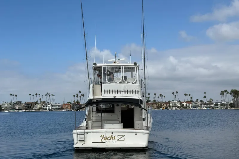 Slide: The Image of 1998 Riviera Convertible yacht on calm water with coastal homes and palm trees in the background. - 49