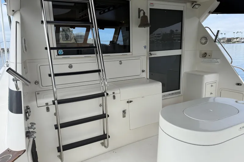 Slide: The Image of 1998 Riviera Convertible yacht interior with ladder, storage, and seating by the water. - 7