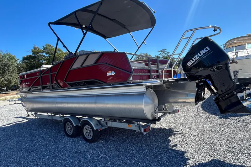 Slide: The Image of 2023 Crest Caribbean Platinum 230 pontoon boat with red and black design on a trailer. - 2