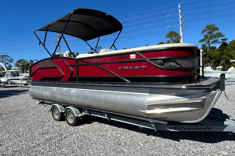 Slide: The Image of 2023 Crest Caribbean Platinum 230 pontoon boat on trailer, under clear blue sky. - 3
