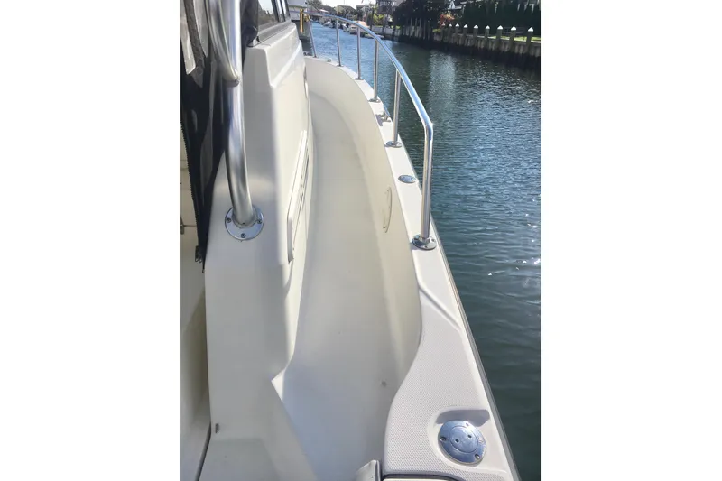 Slide: The Image of 2002 Shamrock 290 Walkaround boat deck with railing, docked by calm water. - 11