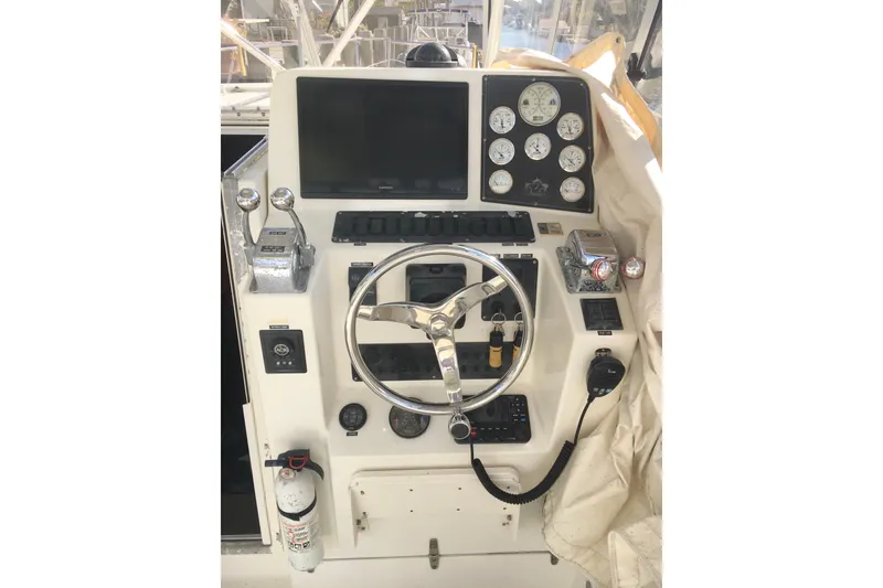 Slide: The Image of 2002 Shamrock 290 Walkaround boat dashboard with steering wheel and control gauges. - 12