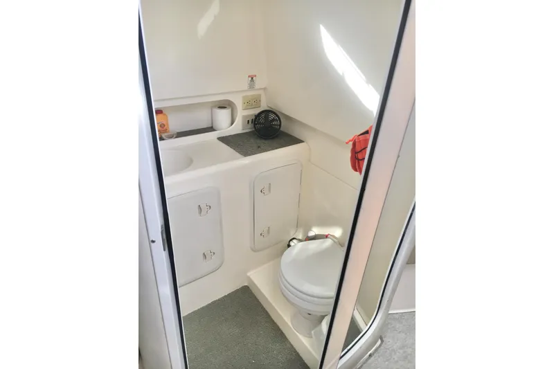 Slide: The Image of 2002 Shamrock 290 Walkaround boat bathroom with sink, toilet, and storage cabinets. - 17