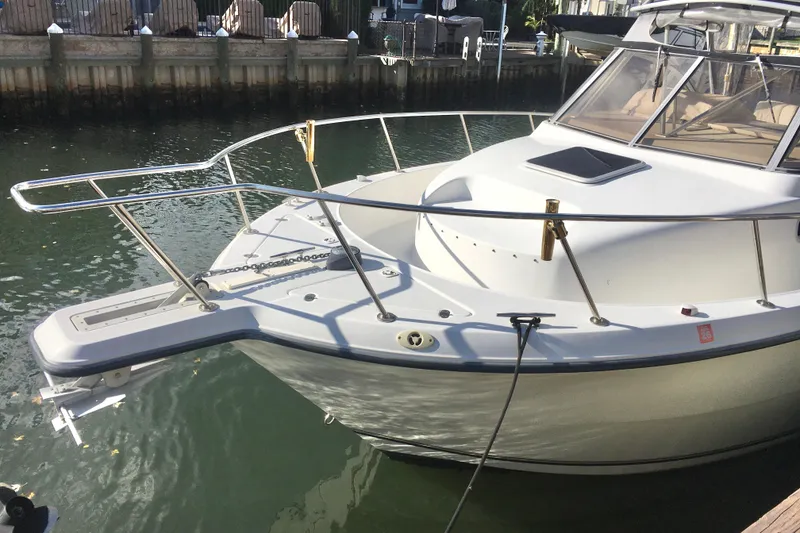 Slide: The Image of 2002 Shamrock 290 Walkaround boat docked in a calm marina setting. - 2