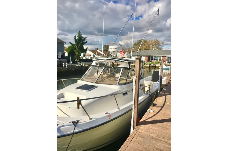 Slide: The Image of 2002 Shamrock 290 Walkaround boat docked at a marina under cloudy skies. - 3