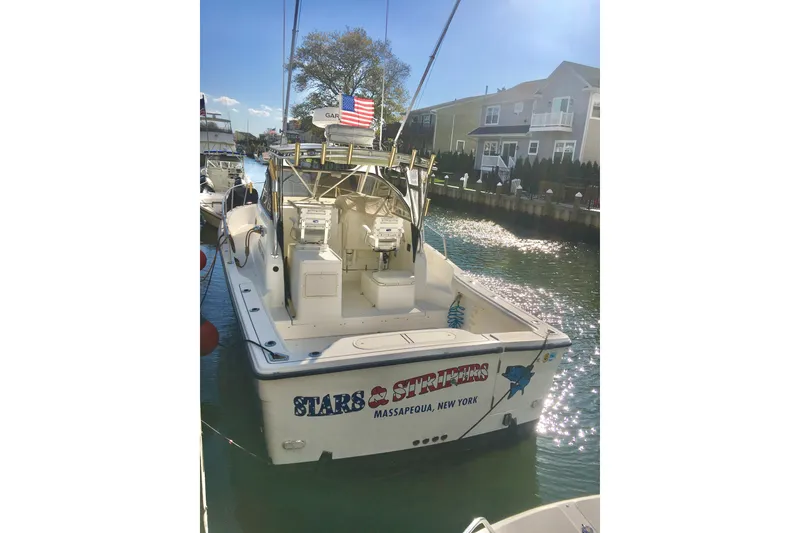 Slide: The Image of 2002 Shamrock 290 Walkaround boat docked, featuring fishing gear and American flag. - 4