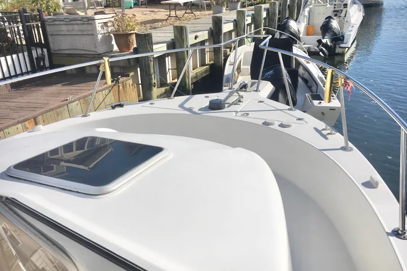 Slide: The Image of 2002 Shamrock 290 Walkaround boat docked by the water, showcasing deck and railing. - 6