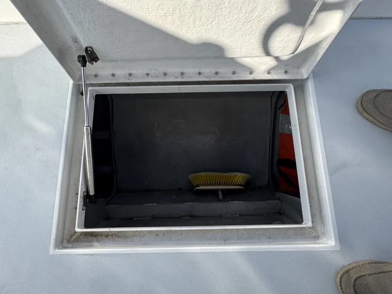 Slide: The Image of Open hatch on FinCat 35 boat, revealing storage compartment with a brush inside. - 13