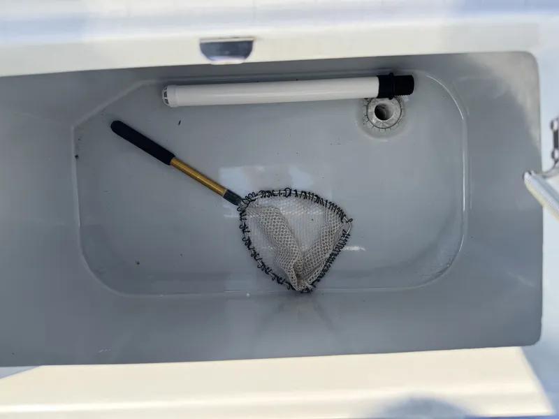 Slide: The Image of Open storage compartment with a fishing net inside a 2005 FinCat 35 boat. - 8