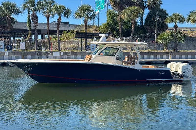The Image of 2019 Scout 355 LXF boat docked in a marina with palm trees in the background. - 0