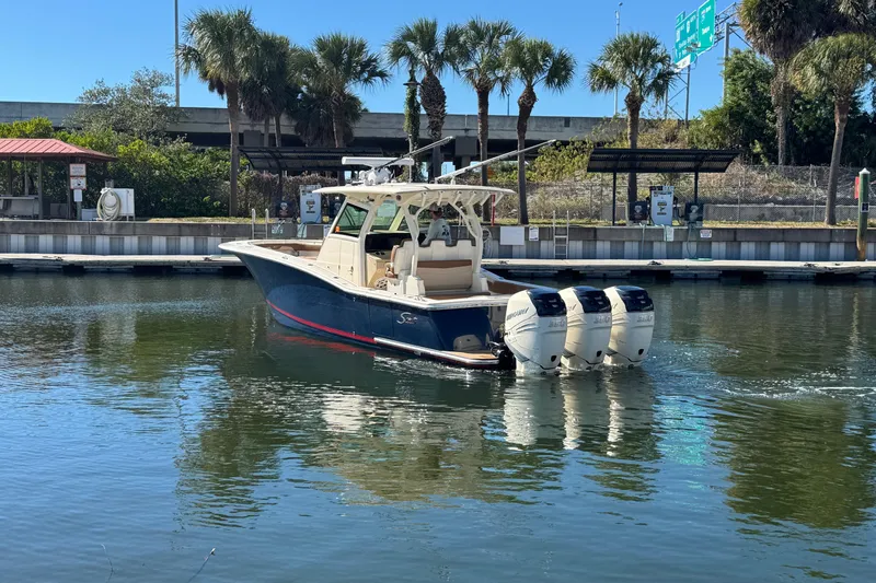 Slide: The Image of 2019 Scout 355 LXF boat with triple outboard engines docked near palm trees. - 1