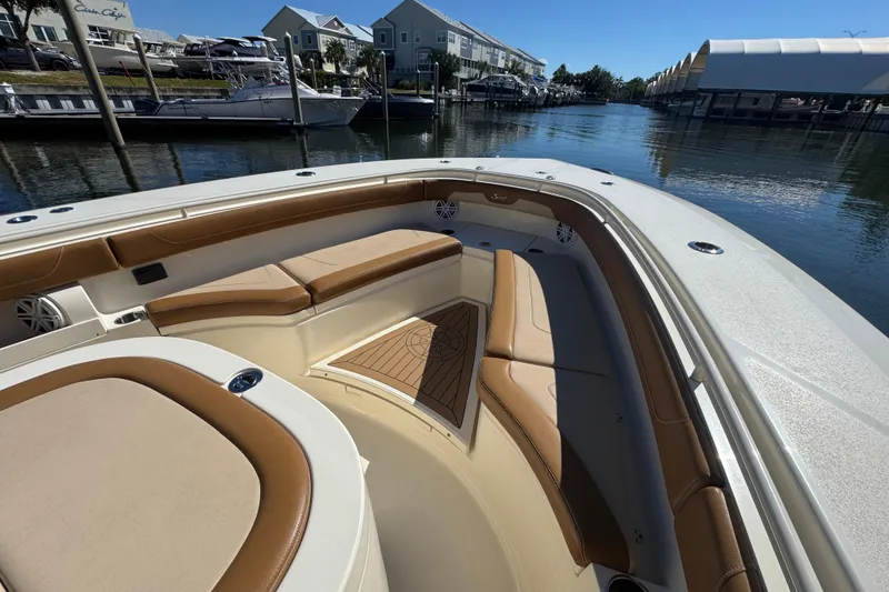 Slide: The Image of 2019 Scout 355 LXF boat interior with tan seating, docked in a marina. - 10