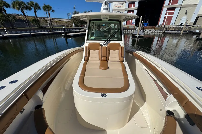 Slide: The Image of 2019 Scout 355 LXF boat with tan seating, docked near a marina. - 11