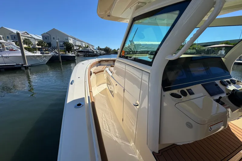 Slide: The Image of 2019 Scout 355 LXF boat docked in a marina under clear blue skies. - 15