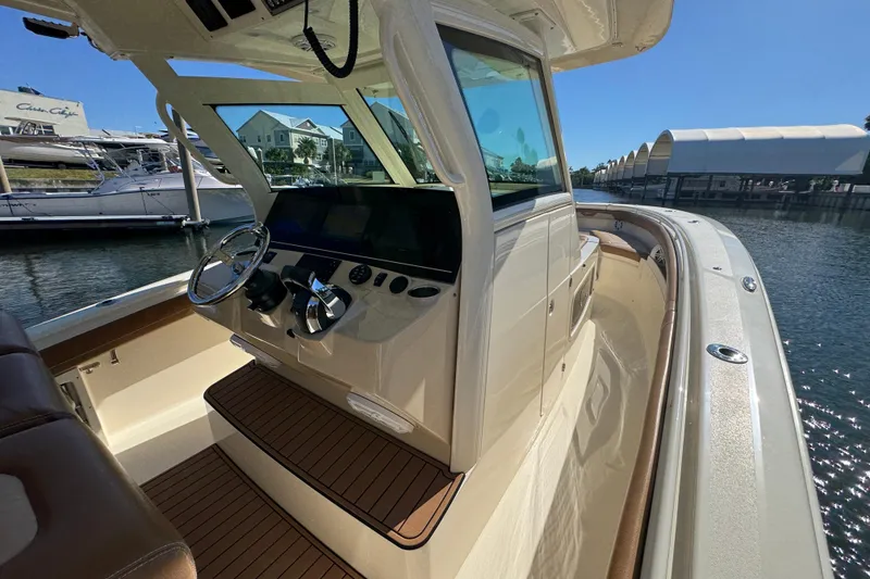Slide: The Image of 2019 Scout 355 LXF boat interior with helm, docked in marina under clear sky. - 16