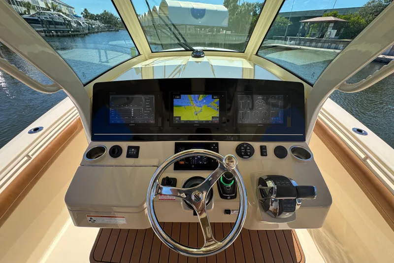 Slide: The Image of 2019 Scout 355 LXF boat dashboard with navigation screens and steering wheel. - 18