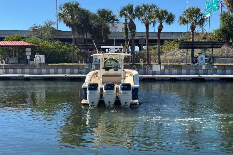 Slide: The Image of 2019 Scout 355 LXF boat with triple engines docked near palm trees. - 2