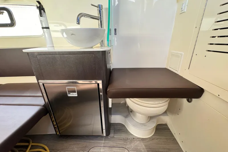 Slide: The Image of 2019 Scout 355 LXF boat interior with sink, seating, and compact toilet. - 27