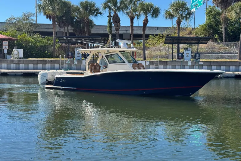 Slide: The Image of 2019 Scout 355 LXF boat docked near palm trees and water. - 5